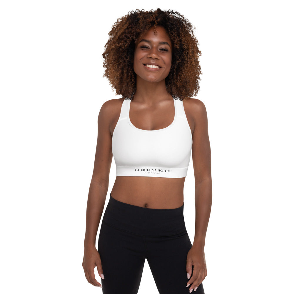 Front view of a smiling woman wearing a white Guerilla Choice padded sports bra with a scoop neckline and racerback, paired with black leggings.