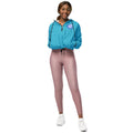 Model wearing a bright blue cropped windbreaker with a half-zip front and adjustable drawstring waist.