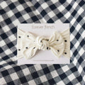 Annie baby head wrap in cream off-white with charcoal black polka dots and a bow