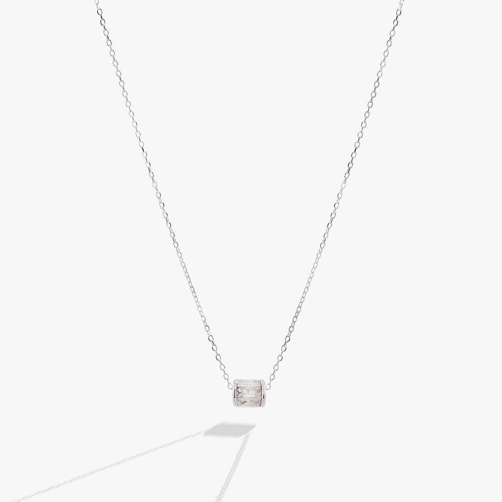 April birthstone pendant necklace with clear baguette crystals and a sliding barrel charm in gold.