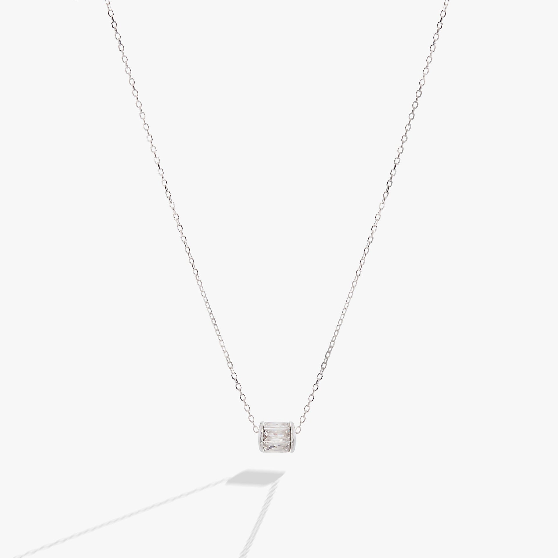 April birthstone pendant necklace with clear baguette crystals and a sliding barrel charm in gold.
