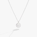 Close up of an Aquarius zodiac necklace featuring a double-sided engraved charm with crystal accents.