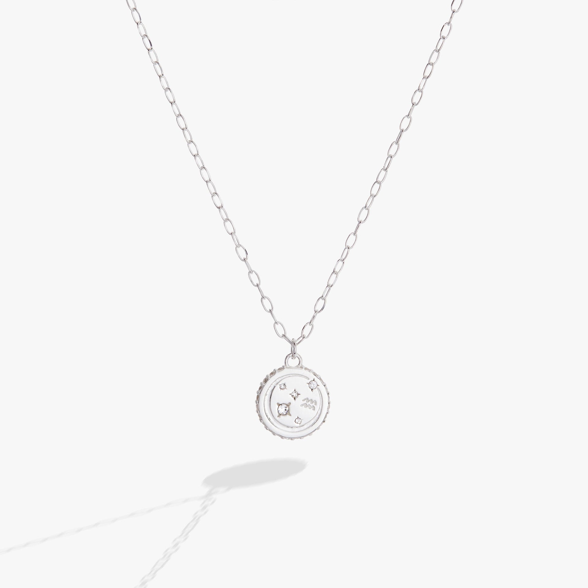 Close up of an Aquarius zodiac necklace featuring a double-sided engraved charm with crystal accents.