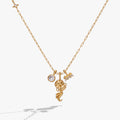 Close up of an Aquarius zodiac charm cluster necklace with crystal pavé on a gold-tone chain.