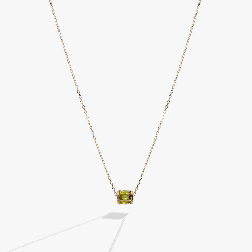 Sliding barrel-shaped pendant necklace featuring peridot-toned green baguette crystals in gold vermeil setting.