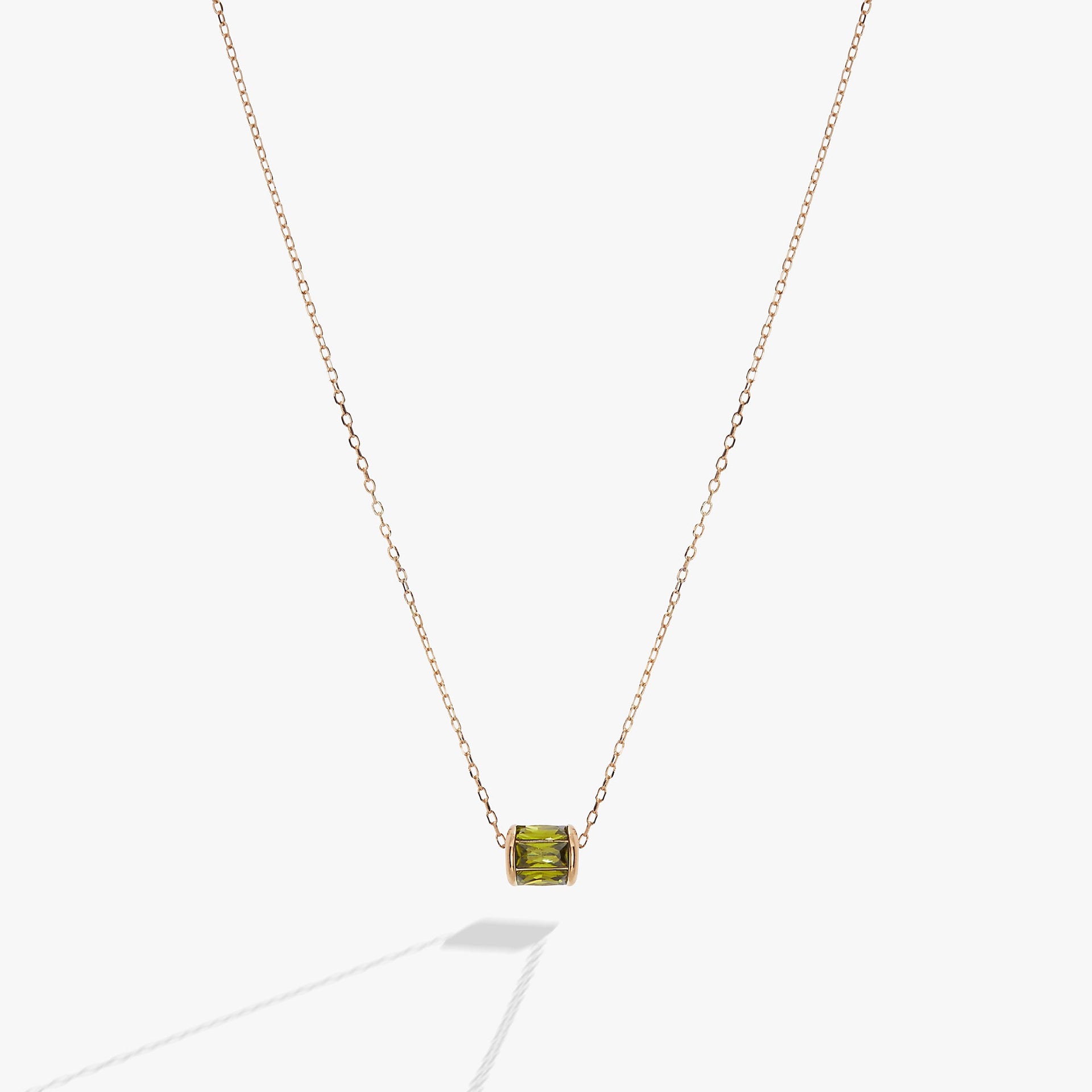 Sliding barrel-shaped pendant necklace featuring peridot-toned green baguette crystals in gold vermeil setting.