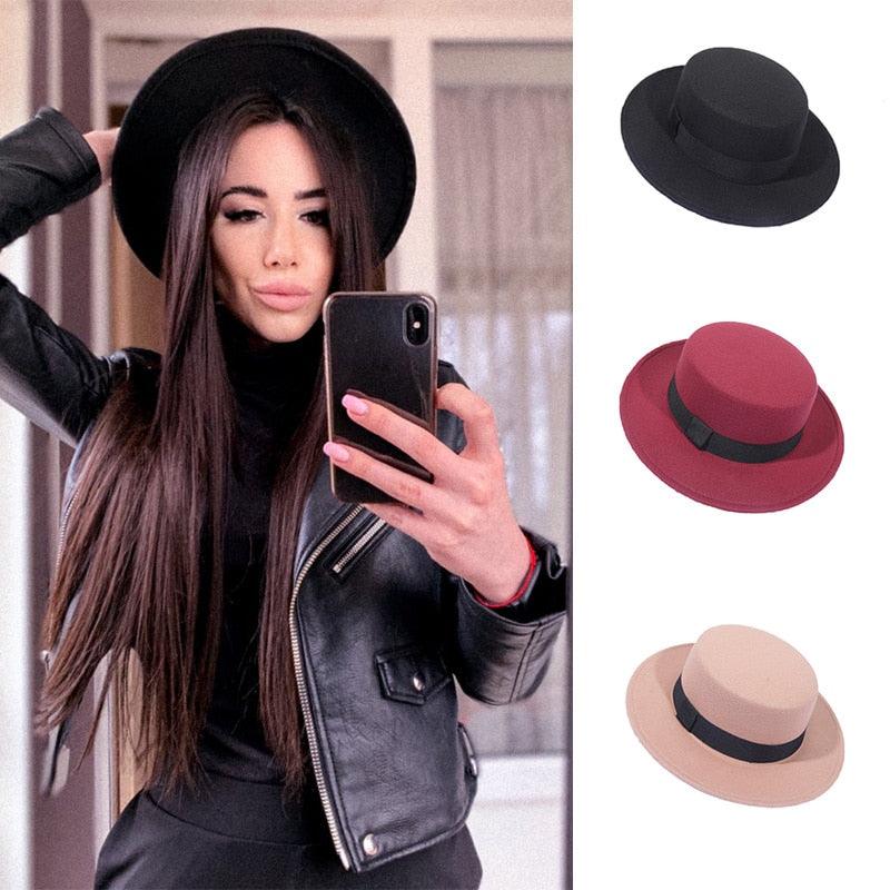 A stylish women's wide brim fedora hat with a flat top and vintage pattern in a sunny outdoor setting.