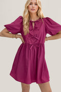 A vintage-inspired mini dress with ruched puff sleeves and a bow detail.
