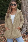 A woman wearing a beige relaxed-fit quilted hooded puffer coat with snap buttons in a casual lifestyle setting.