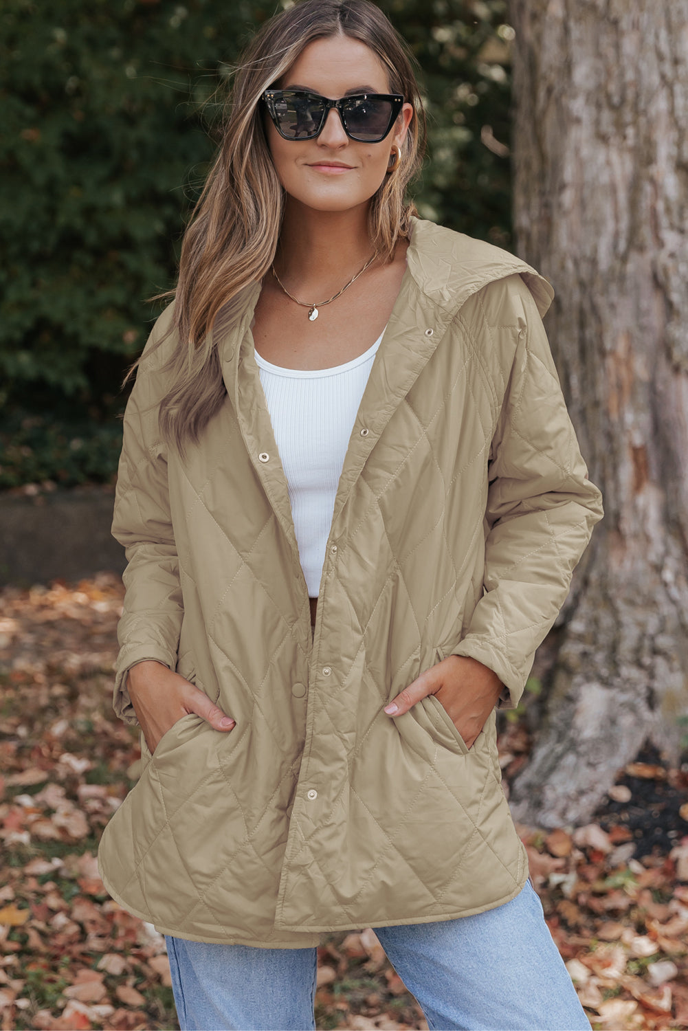 A woman wearing a beige relaxed-fit quilted hooded puffer coat with snap buttons in a casual lifestyle setting.
