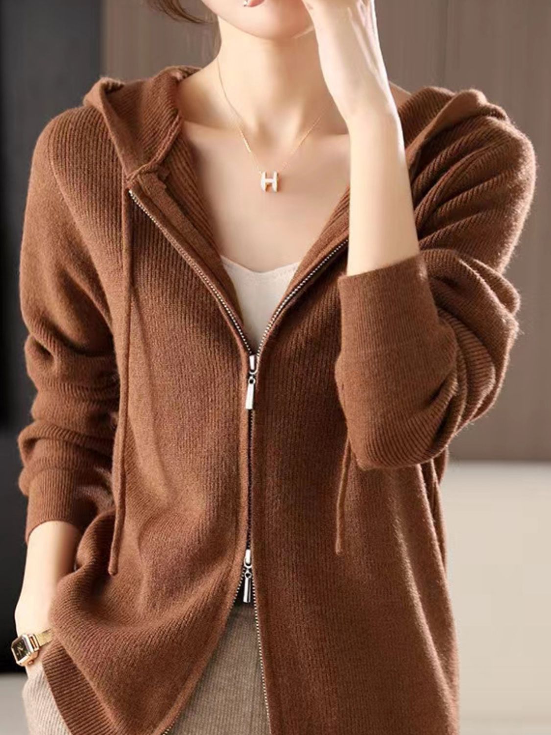 Model wearing a brown long sleeve zip-up hooded knit sweater with drawstring detail