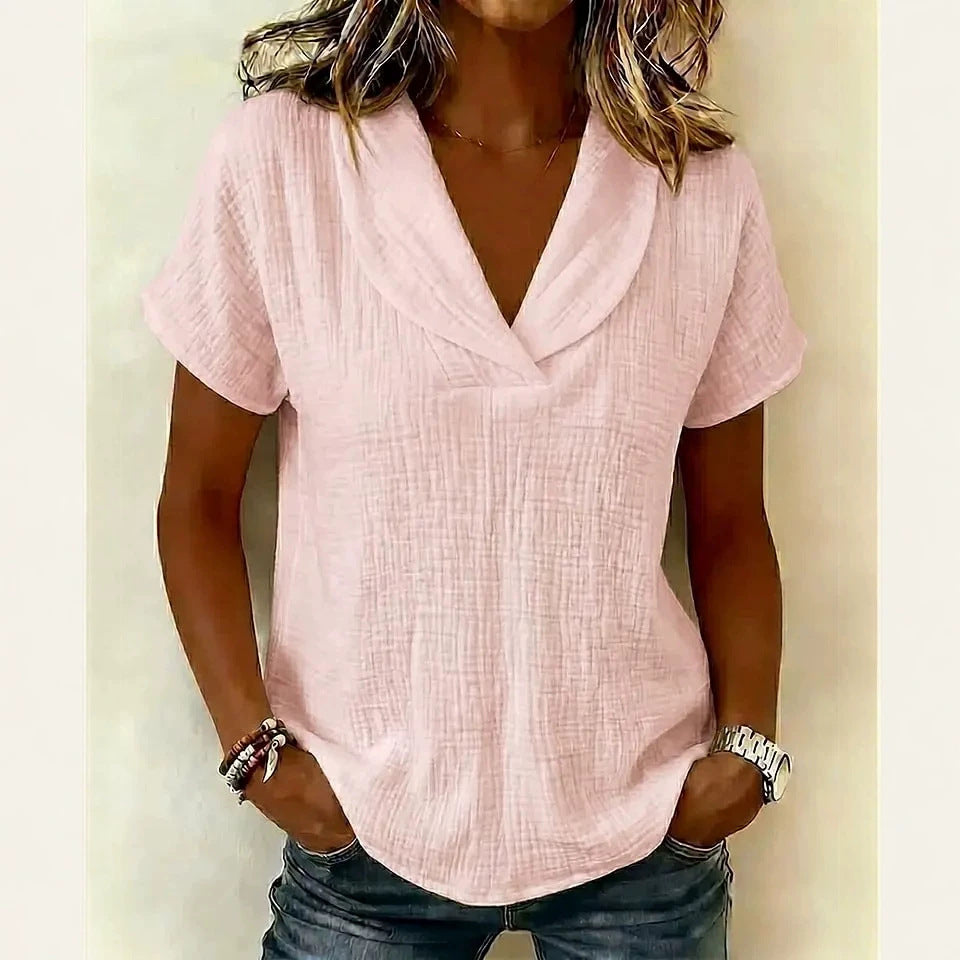 A woman wearing a short-sleeve butterfly collar top in light pink, paired with jeans.