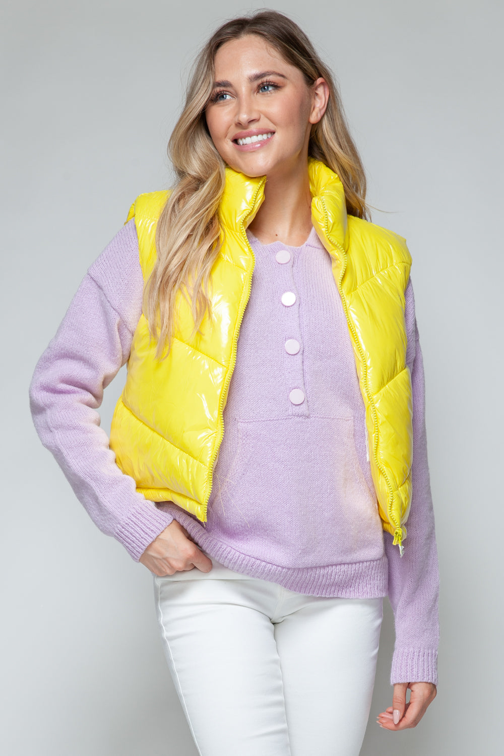 A woman wearing a bright yellow, high-shine quilted vest with a turtleneck over a lavender sweater, viewed from the front and back.
