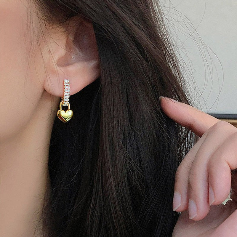 Pair of dainty gold heart stud earrings on a clean white background