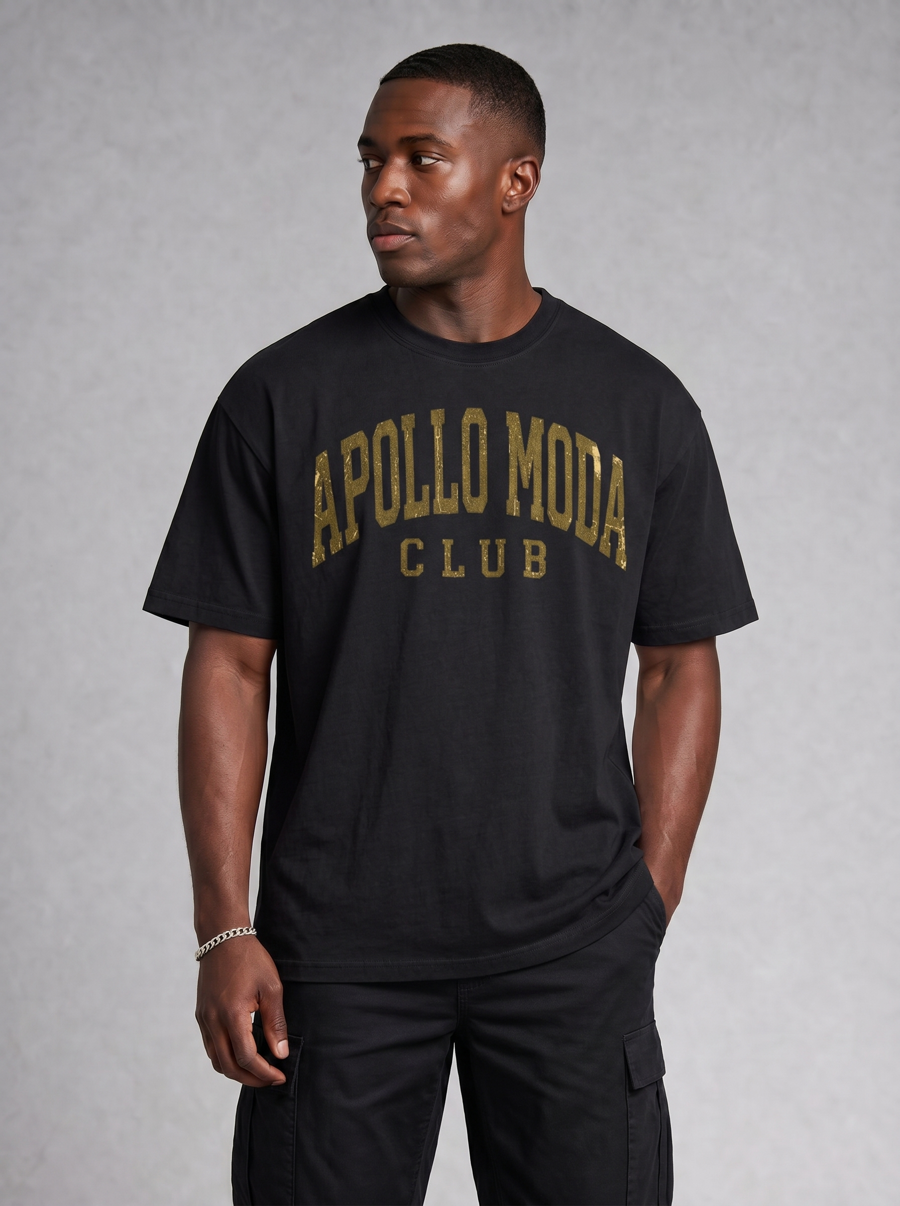 Model wearing a black oversized t-shirt with distressed metallic gold collegiate lettering