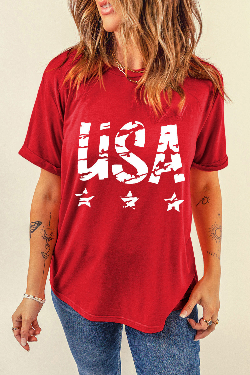 Model wearing a red short sleeve t-shirt with white USA text and star graphic, styled with blue jeans.