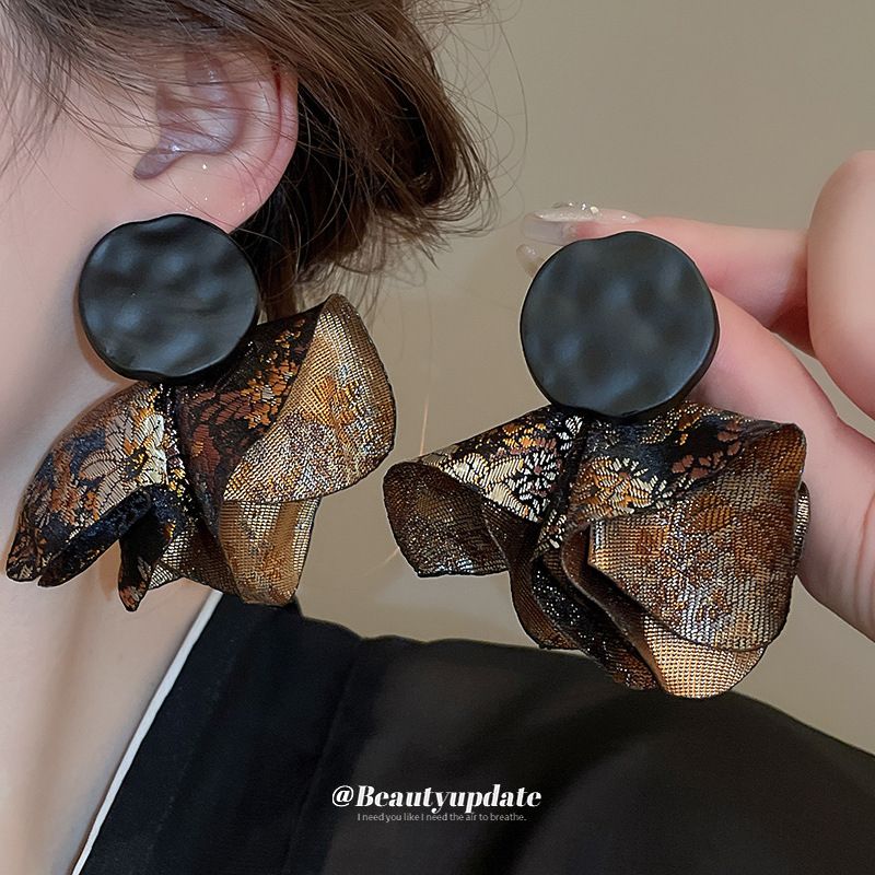 Close-up of elegant pleated round petal dangle earrings with silver posts.