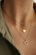 Leah Layered Heart Necklace Set featuring three polished gold chains displayed elegantly.