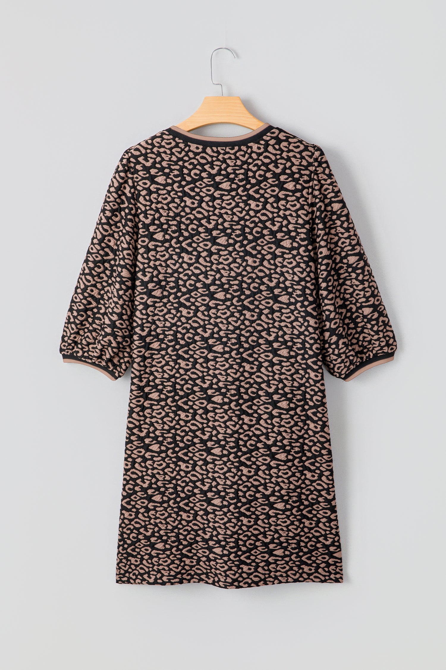 Leopard print dress on a hanger against a light gray background