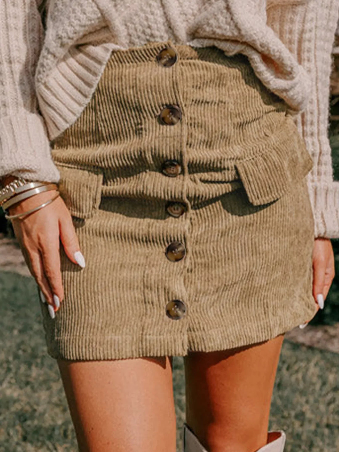 Tan button-front corduroy mini skirt with faux pocket flaps on a hanger