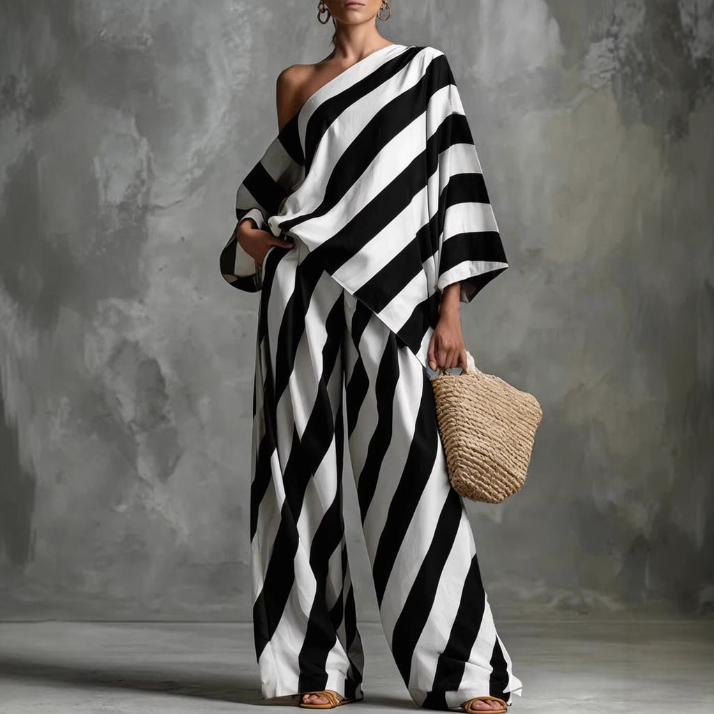 A woman wearing a one-shoulder batwing top and matching wide-leg pants with a bold diagonal stripe pattern.