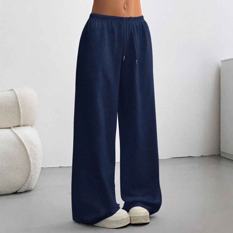 Model wearing straight-leg navy blue drawstring sweatpants with platform sneakers