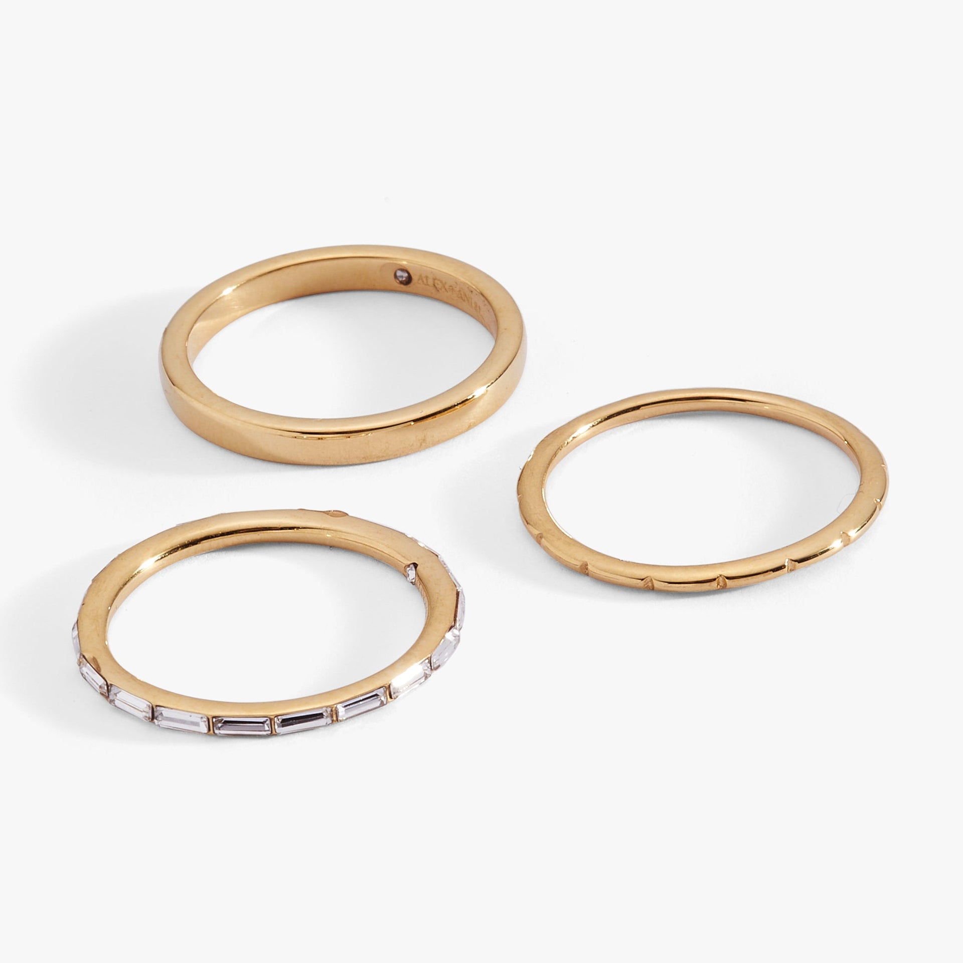 Alex And Ani set of three stacking rings featuring a faceted band, a clear baguette crystal band, and a smooth square band.