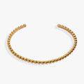 Gold beaded textured cuff bracelet worn on a wrist, featuring a light-catching design.
