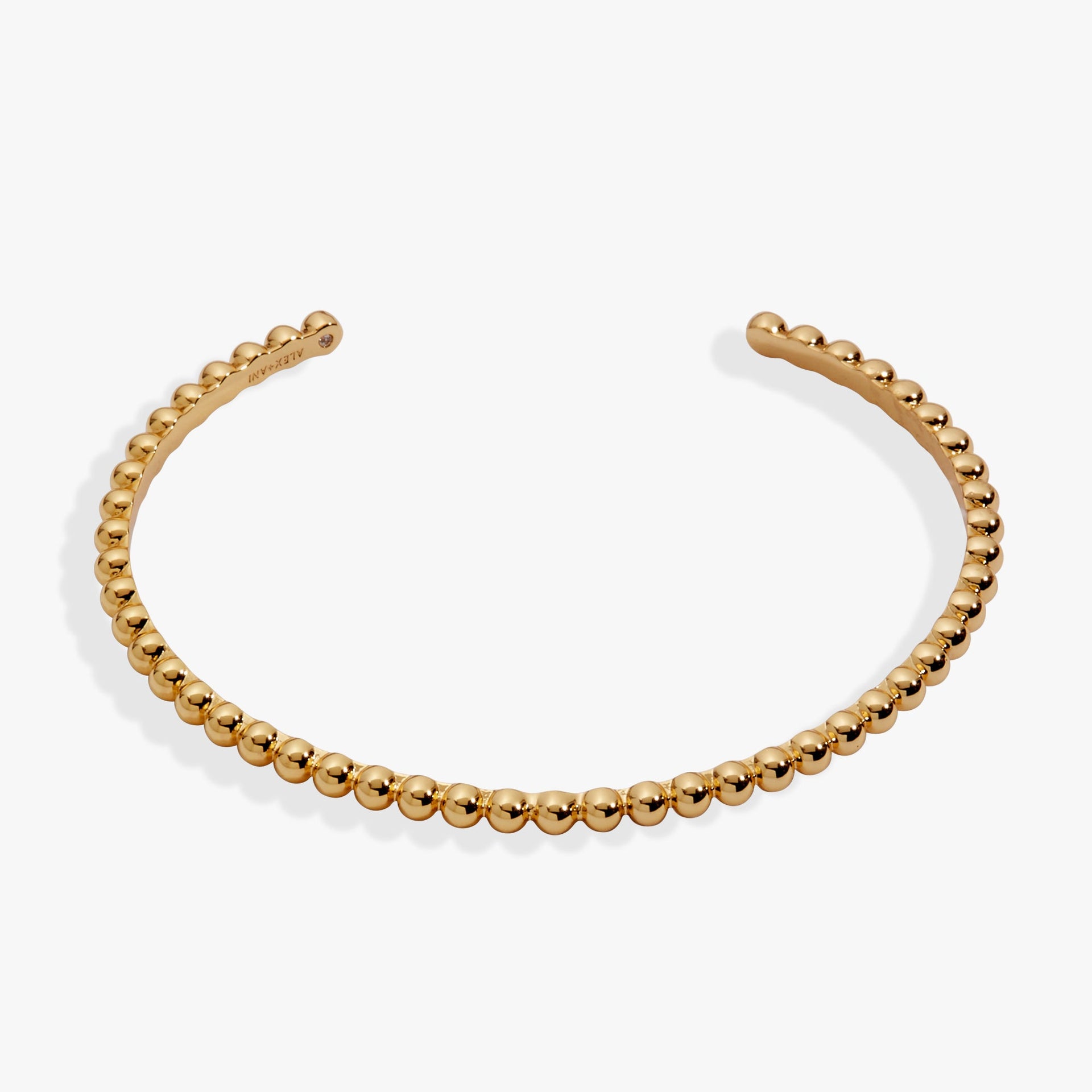 Gold beaded textured cuff bracelet worn on a wrist, featuring a light-catching design.