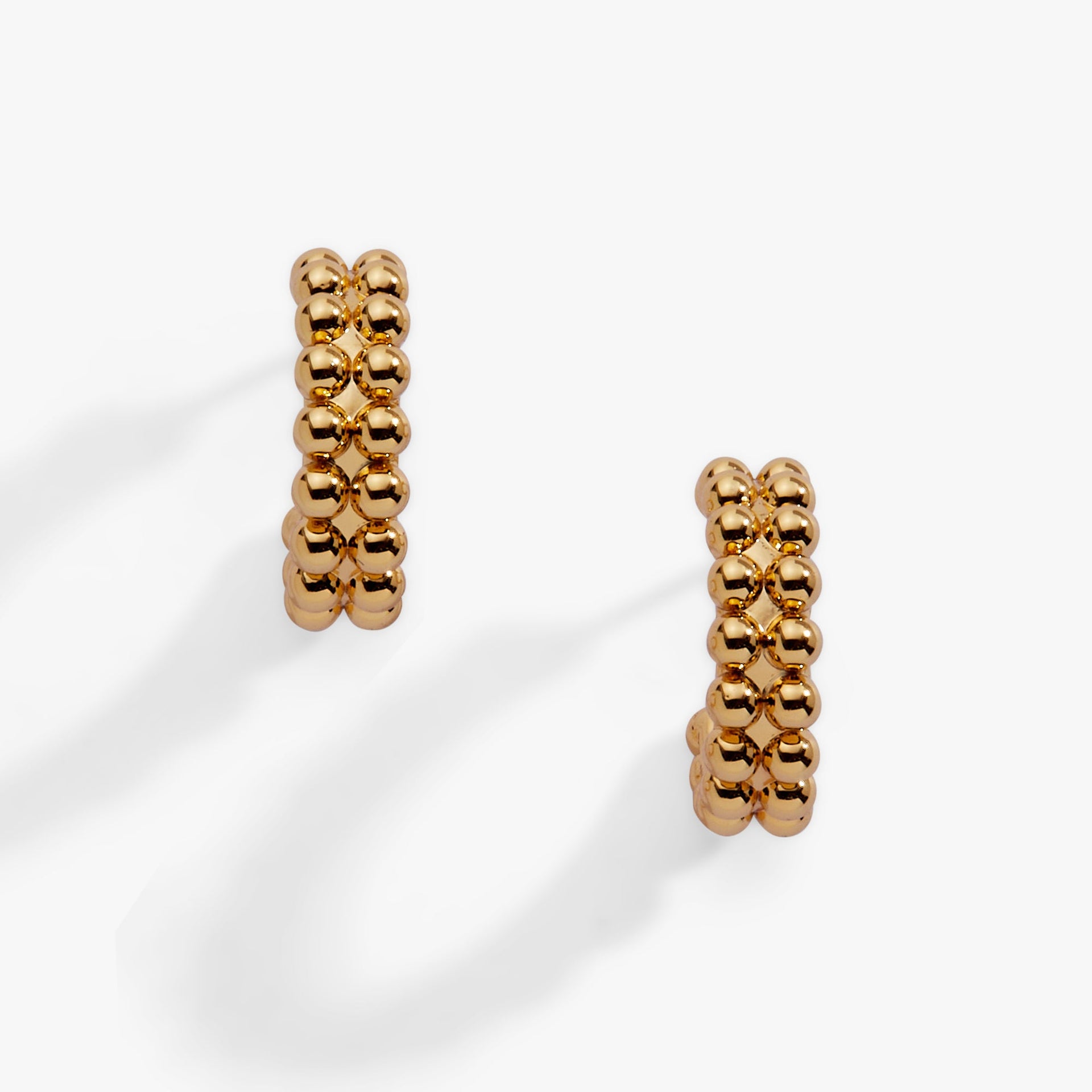 A pair of gold-plated huggie hoop earrings featuring a textured beaded ball design.