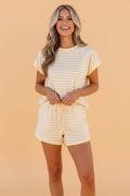 Woman wearing a pastel yellow and lavender striped knit t-shirt and matching drawstring shorts set.