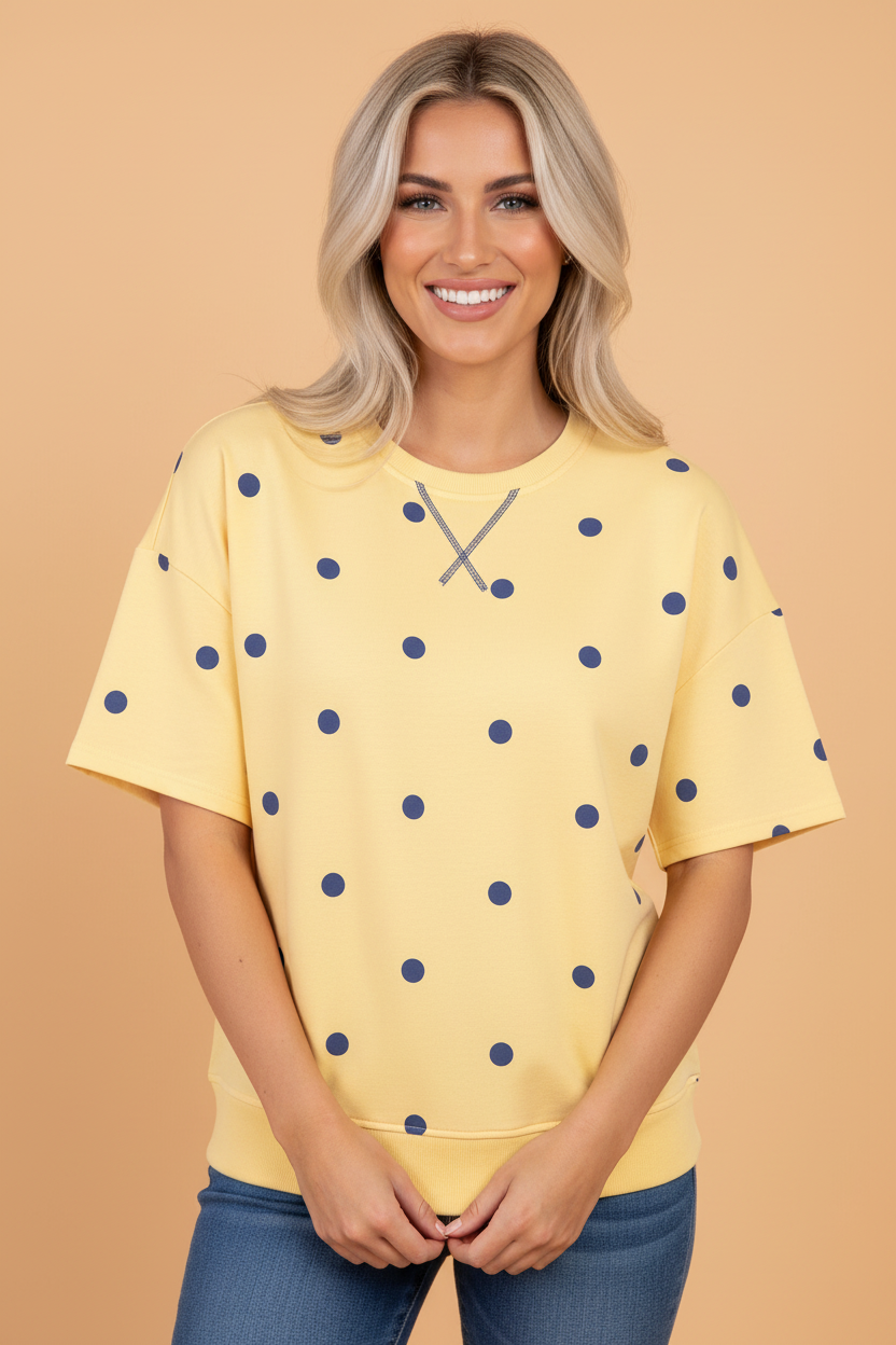Woman wearing a bright yellow retro polka dot oversized cotton tee with navy blue print and crew neckline.