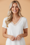 Close up of white V-neck T-shirt with hollowed lace trim detailing.