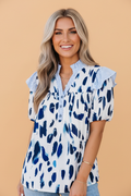 Woman wearing an abstract leopard and stripe print V-neck blouse with ruffle trim sleeves in white and blue