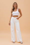 Woman wearing high waist white wide leg denim jeans, styled with a minimalist casual aesthetic
