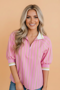 A woman wearing a vibrant striped half-zip blouse with 3/4 sleeves and a collared neckline.