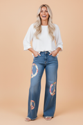 Medium blue wide-leg denim jeans with floral peace sign embroidery and raw edge hem