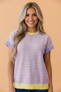 Women wearing a lavender, pale yellow, and white colorblock striped knit t-shirt with crew neck and short sleeves.