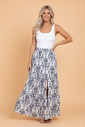A woman wearing a bohemian tiered maxi skirt with a floral print and side split in orange and white.