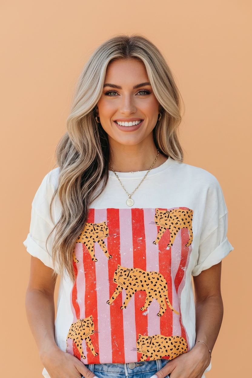 Woman wearing a vintage-style cheetah stripe graphic tee in off-white with red and pink details.