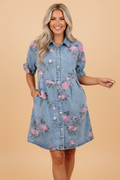 A floral print denim dress with button-down front and collar, featuring short sleeves.