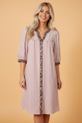 Woman wearing a white, maroon, and brown striped shirt dress with leopard print trim and 3/4 sleeves.