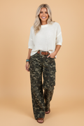 Model wearing high-rise camouflage print denim cargo pants with wide legs and zip-fly closure
