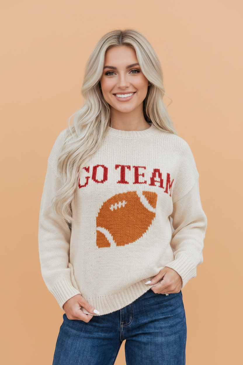 Cream knit sweater with football graphic and 'GO TEAM' lettering, featuring relaxed drop shoulder fit.