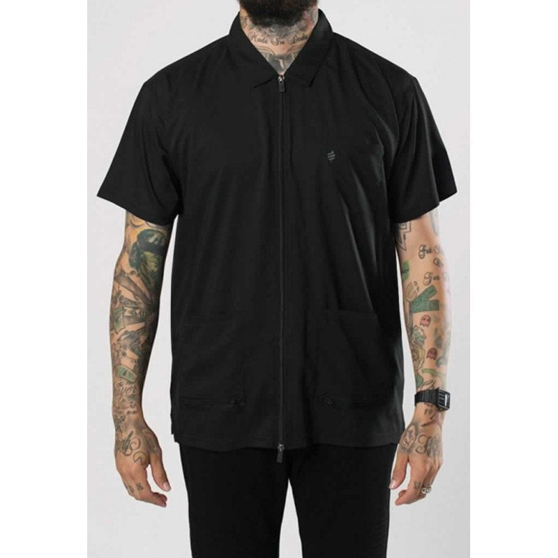 Professional barber wearing a short-sleeve black Barber Jacket with zip closure in a shop setting.