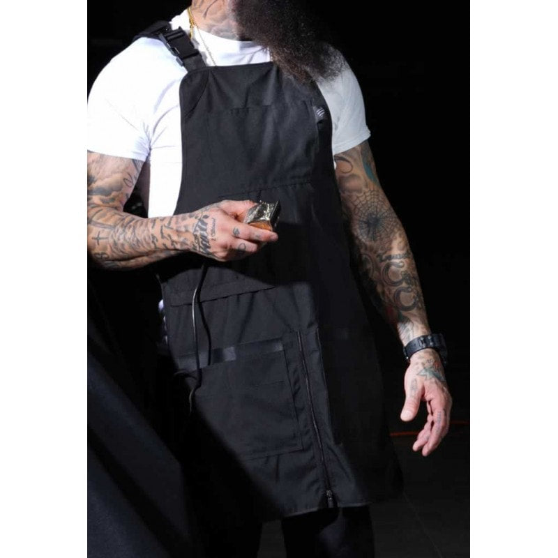Professional barber apron with padded neck strap and multiple tool pockets in a shop setting.