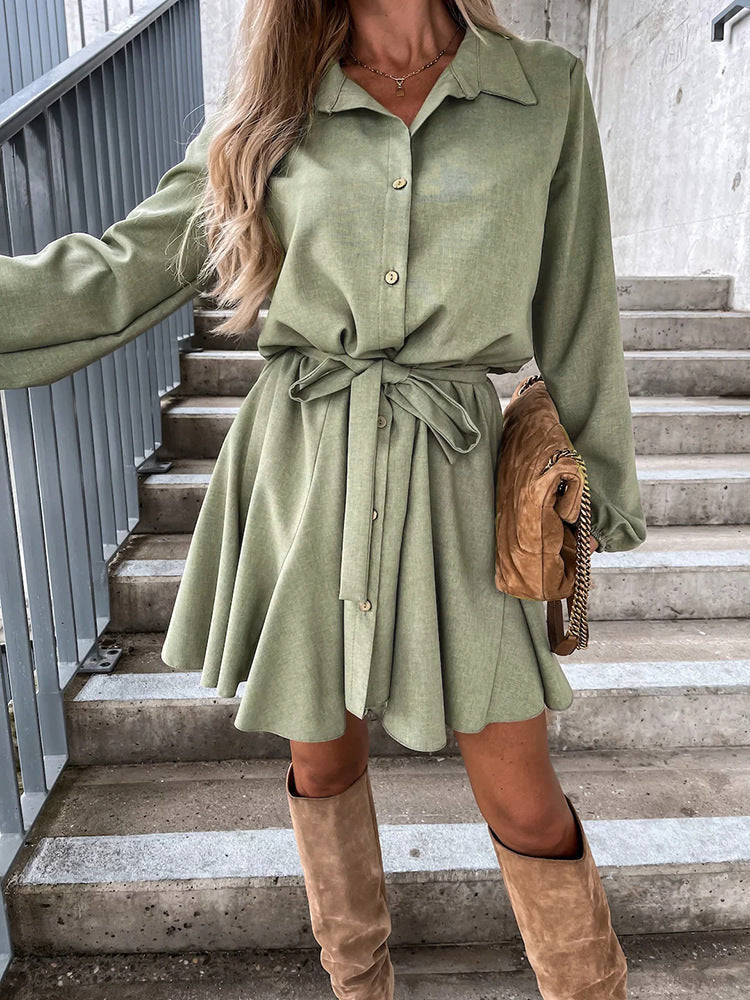 A woman wearing a sage green long sleeve suede mini jumpsuit with a collared neck and button-up front in a lifestyle setting.