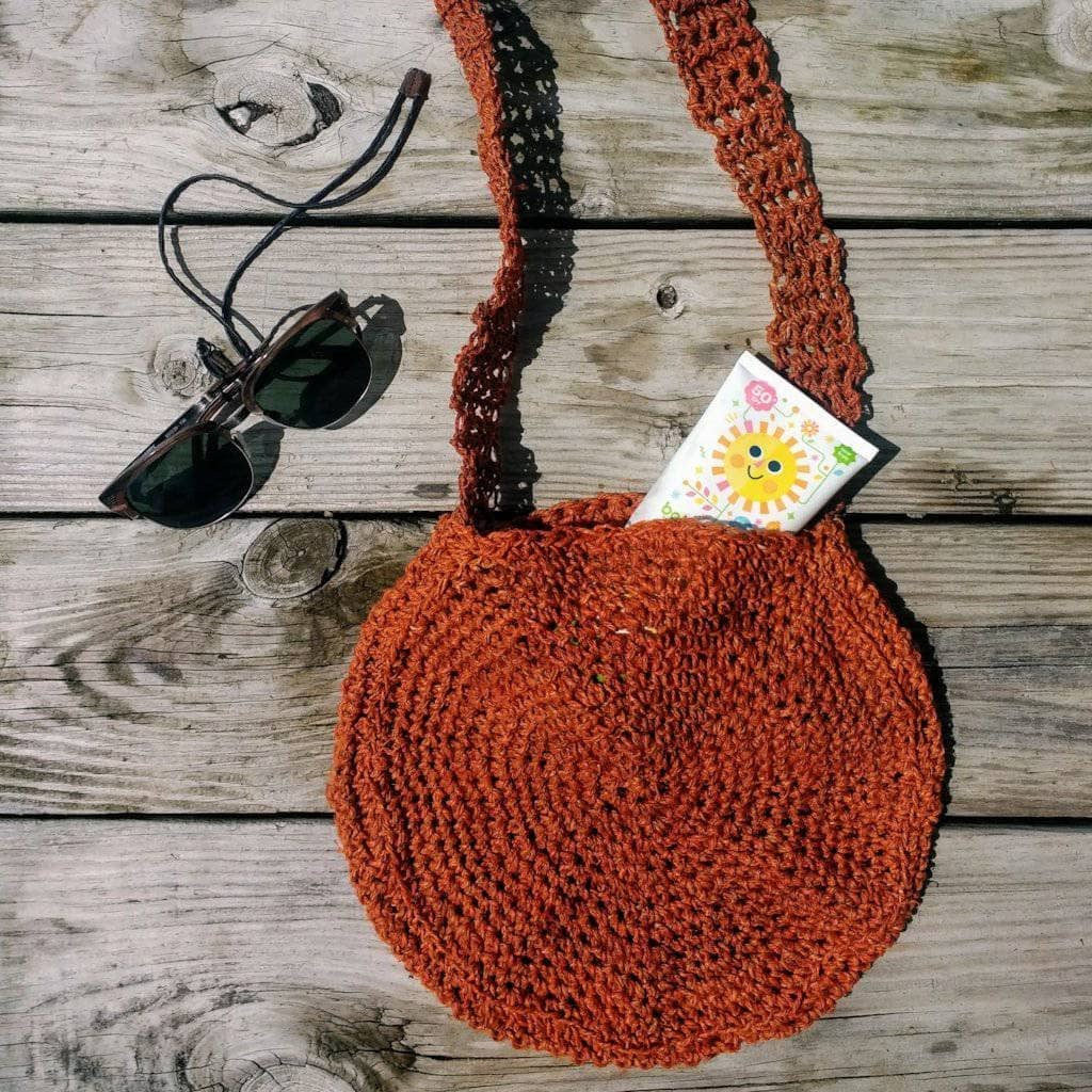 A finished handmade crochet bag made from natural hemp yarn, suitable for beach trips.