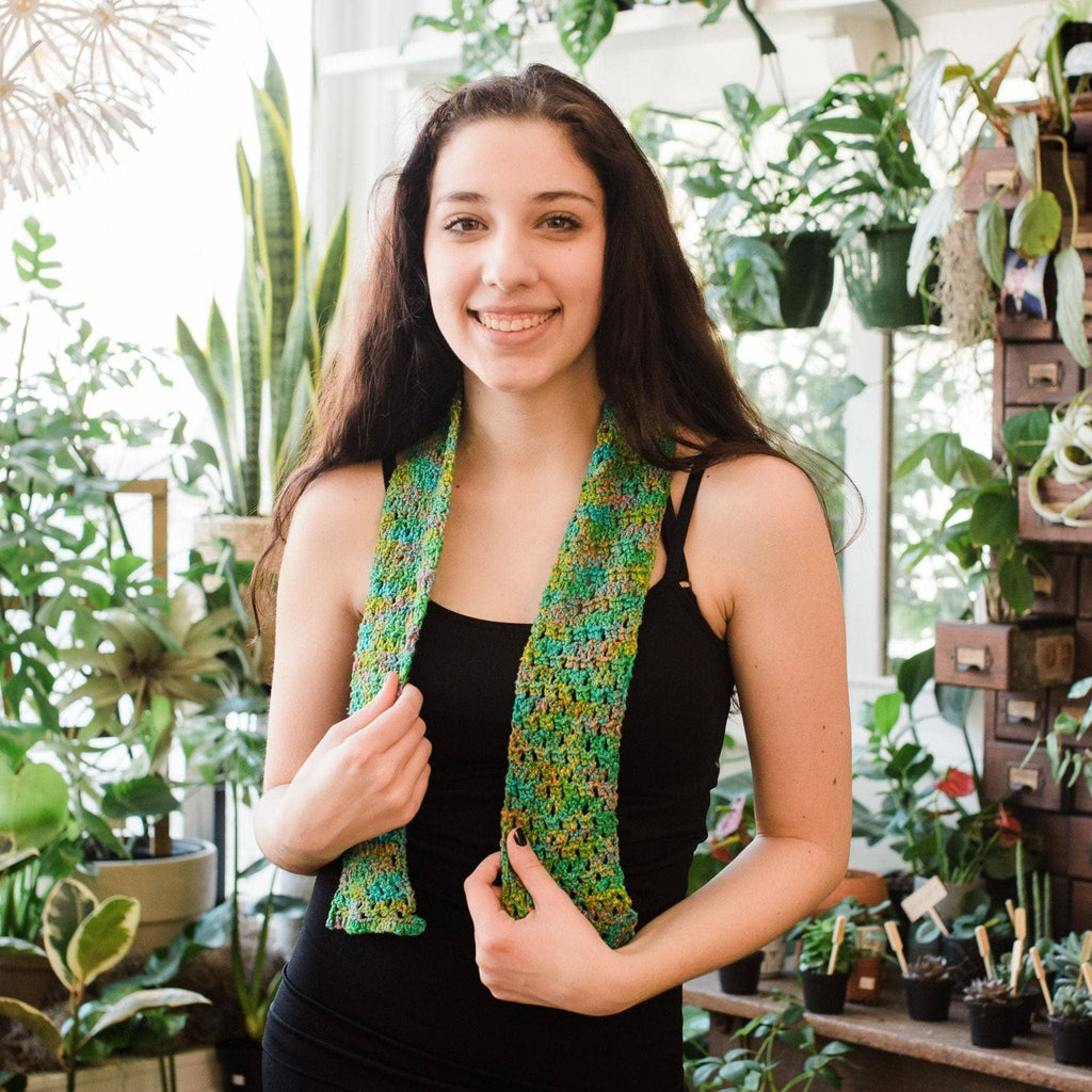 Close up of a beginner knitting and crochet scarf kit in green, brown, and yellow silk yarn