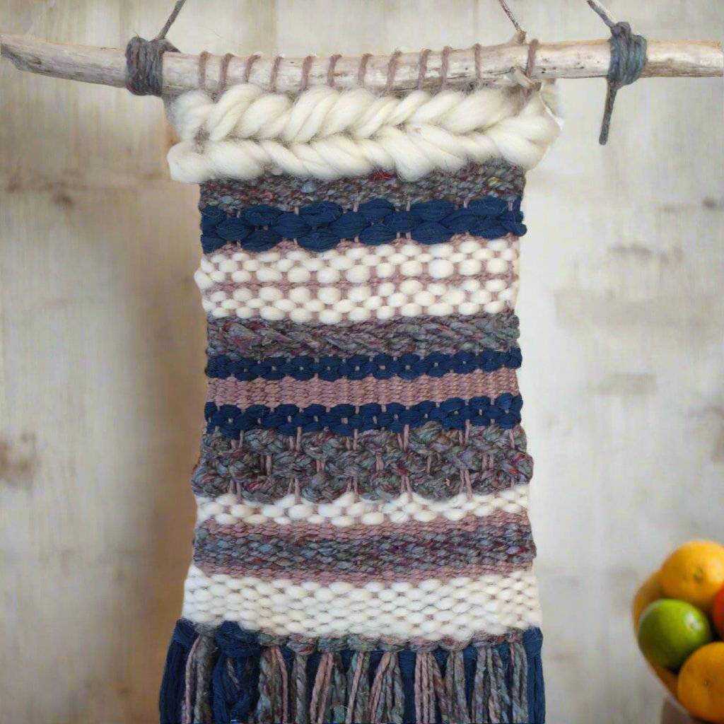 Boho urban striped wall hanging in navy, cream, and earthy tones hanging on a living room wall.
